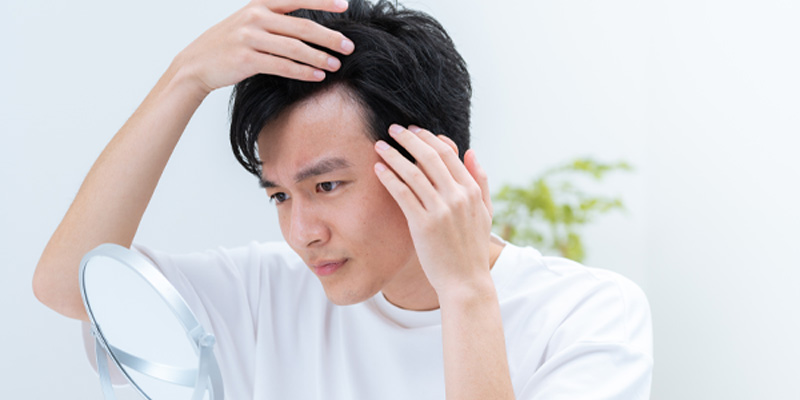 医師が男性の頭皮と毛髪の状態を確認する様子