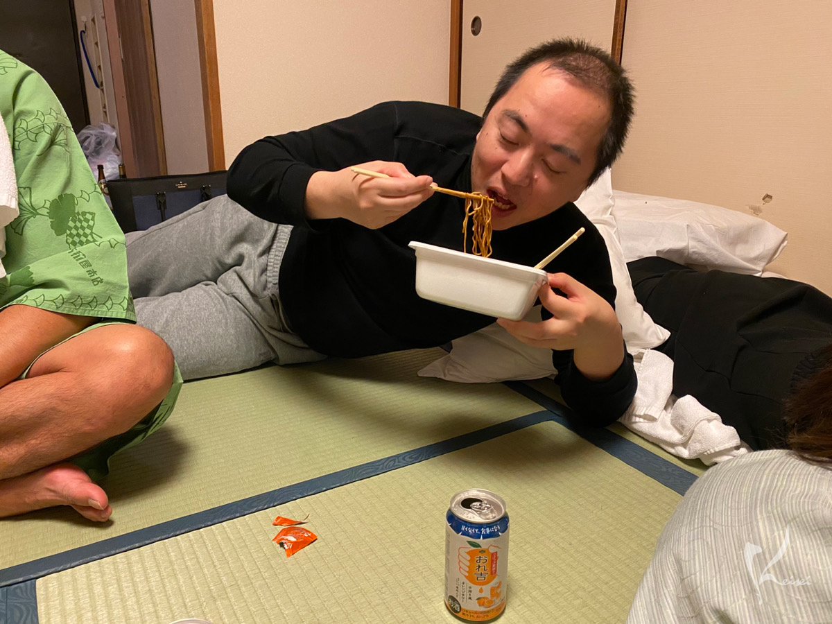 田川先生が寝転んで焼きそばを食べている写真